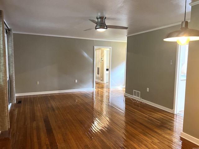 spare room with crown molding, a ceiling fan, visible vents, baseboards, and hardwood / wood-style floors