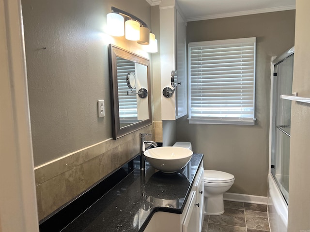 full bathroom featuring vanity, toilet, combined bath / shower with glass door, baseboards, and ornamental molding