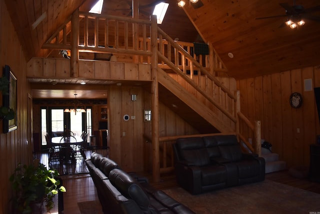 12192 Point Breeze Rd, Parks, AR 72950 - living room featuring high vaulted ceiling, wood walls, ceiling fan with notable chandelier, wood finished floors, and stairway