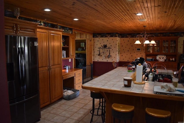 12192 Point Breeze Rd, Parks, AR 72950 - kitchen featuring tile countertops, black refrigerator with ice dispenser, a breakfast bar, and an inviting chandelier