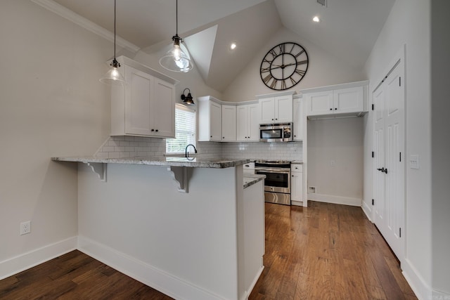 kitchen with a peninsula, light stone countertops, a kitchen bar, white cabinets, and stainless steel appliances