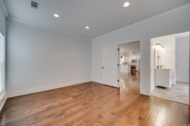 unfurnished room featuring crown molding, light wood finished floors, recessed lighting, baseboards, and visible vents