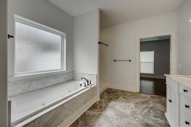 bathroom featuring a jetted tub, vanity, and baseboards
