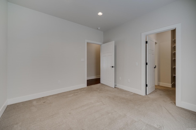 unfurnished bedroom featuring a walk in closet, baseboards, carpet, and recessed lighting
