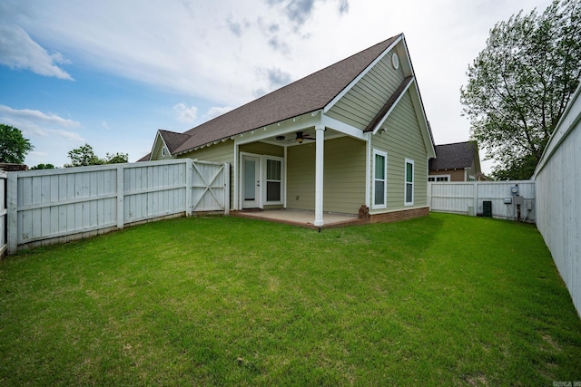 rear view of house with a fenced backyard, a patio, a shingled roof, and a lawn