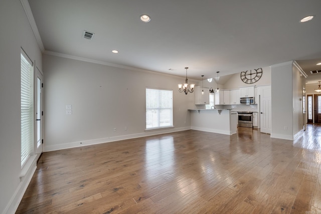 unfurnished living room with an inviting chandelier, crown molding, plenty of natural light, and visible vents