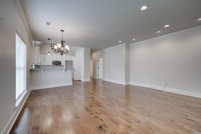 unfurnished living room with an inviting chandelier, crown molding, plenty of natural light, and visible vents