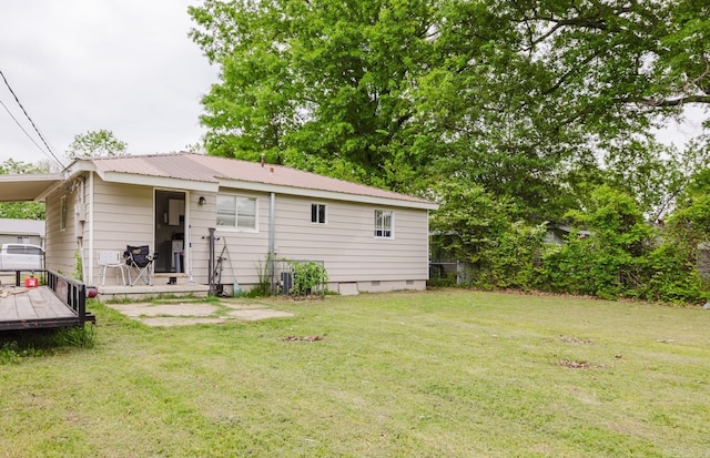 rear view of house with a lawn, a deck, crawl space, and metal roof