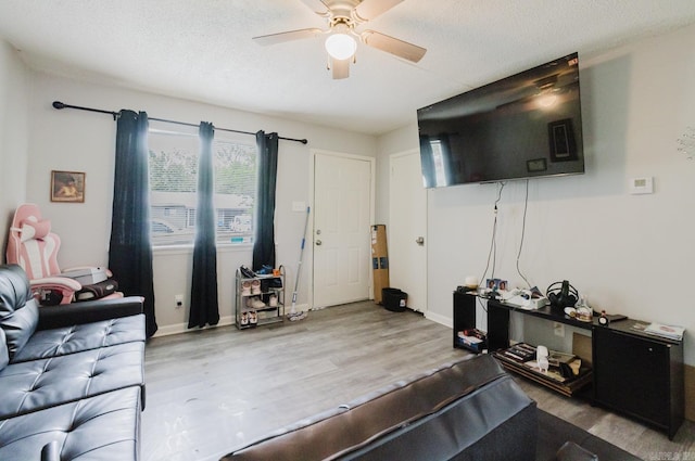 living room with a ceiling fan, a textured ceiling, and wood finished floors