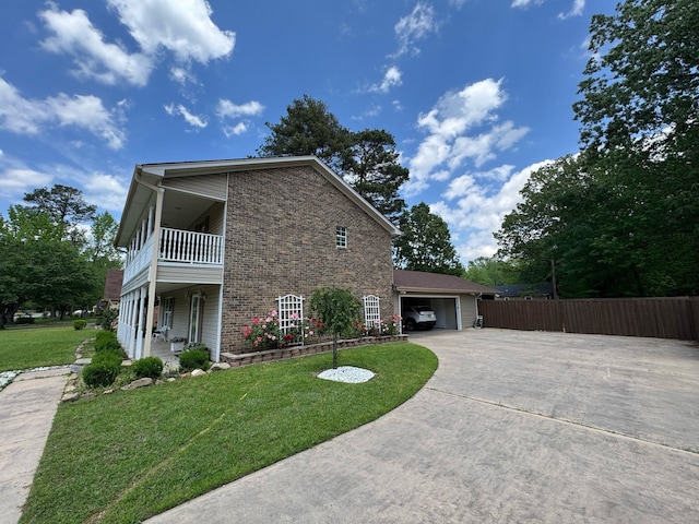 view of property exterior with a yard, fence, a balcony, and concrete driveway
