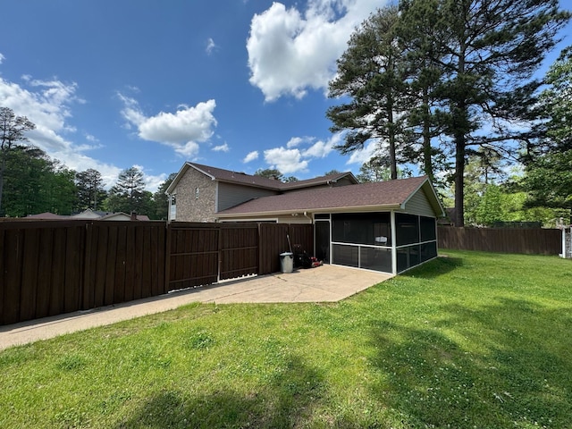 rear view of property featuring a lawn, a patio, a sunroom, and a fenced backyard
