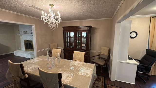 dining space featuring an inviting chandelier, ornamental molding, a brick fireplace, a textured ceiling, and dark wood finished floors