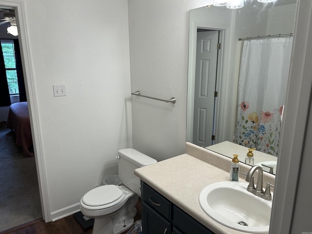 bathroom with wood finished floors, vanity, baseboards, toilet, and ensuite bath