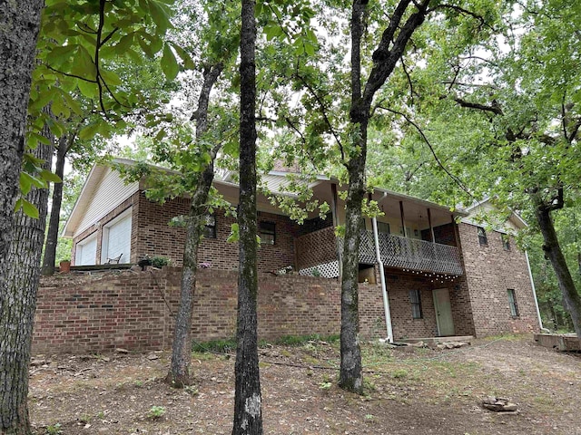 rear view of house featuring a balcony and brick siding