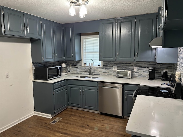 kitchen featuring appliances with stainless steel finishes, a sink, dark wood finished floors, tasteful backsplash, and visible vents