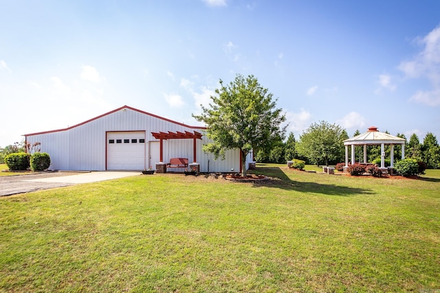 view of yard featuring a garage, a pole building, concrete driveway, a gazebo, and an outbuilding