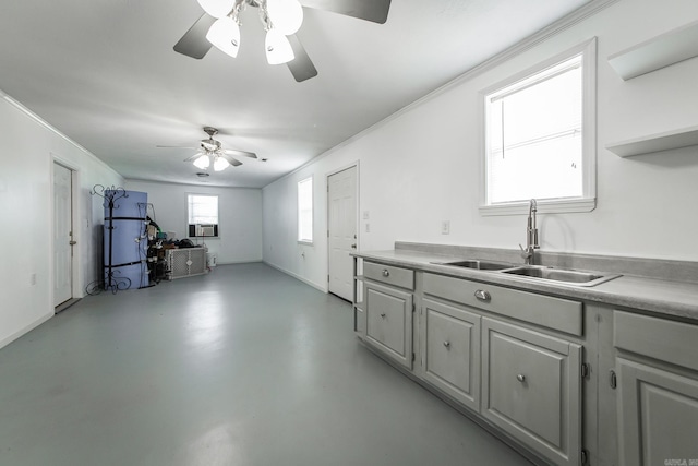 kitchen featuring a ceiling fan, crown molding, a sink, light countertops, and concrete floors