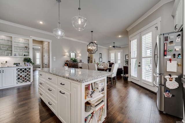 kitchen with crown molding, open shelves, light stone counters, freestanding refrigerator, and white cabinetry