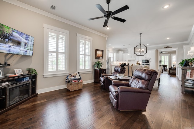 living area featuring visible vents, crown molding, ceiling fan with notable chandelier, and a healthy amount of sunlight