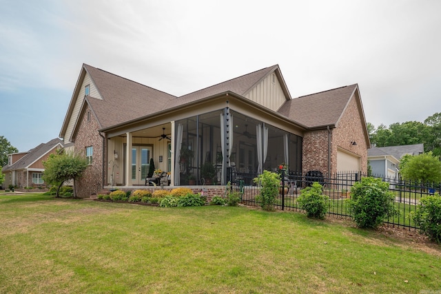 rear view of property featuring fence, brick siding, ceiling fan, french doors, and a lawn