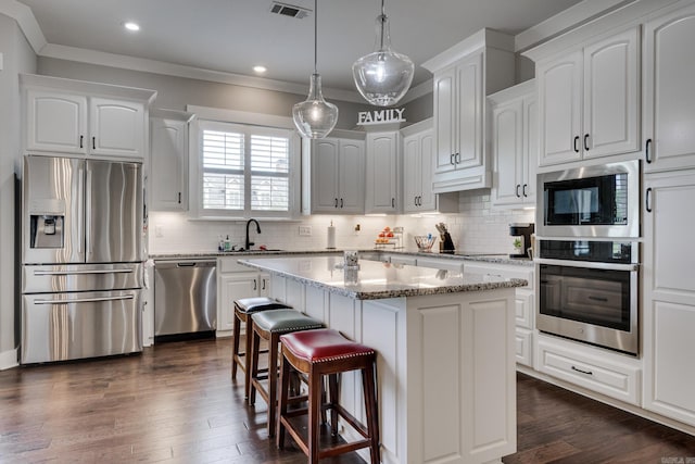 kitchen with visible vents, a breakfast bar area, white cabinets, a sink, and appliances with stainless steel finishes
