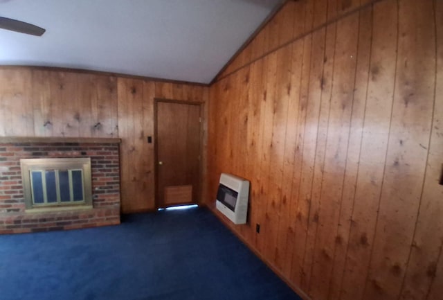 unfurnished living room with dark colored carpet, wood walls, heating unit, and vaulted ceiling