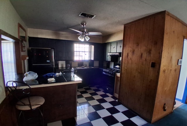 kitchen featuring a ceiling fan, visible vents, fridge, dark floors, and under cabinet range hood