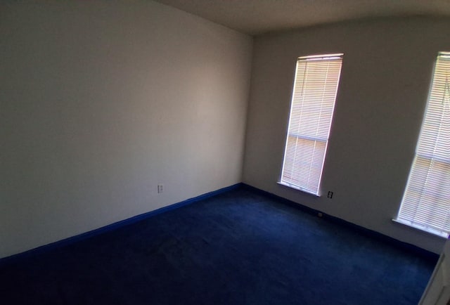 empty room featuring dark carpet and baseboards