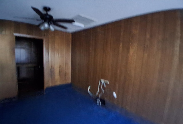 interior space featuring wooden walls and a ceiling fan