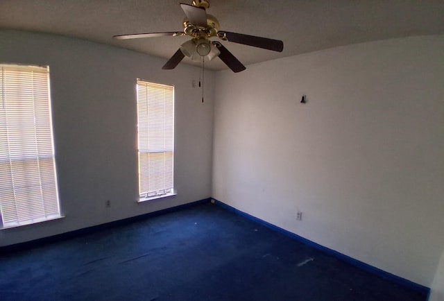 carpeted empty room with baseboards and a ceiling fan