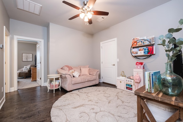 living area featuring visible vents, a ceiling fan, baseboards, and wood finished floors