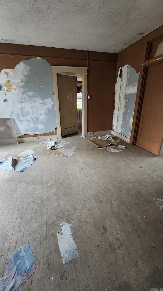 unfurnished room featuring wood-type flooring and a textured ceiling
