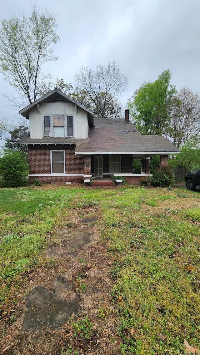 back of property with brick siding, a lawn, a chimney, and a porch
