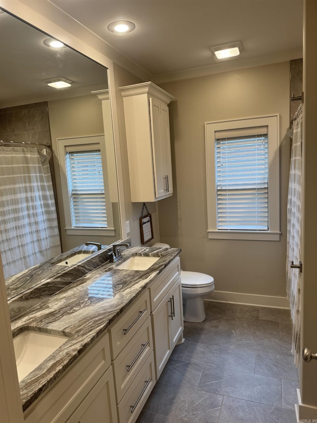 2560 Lilac Dr, Conway, AR 72034 - bathroom with baseboards, toilet, double vanity, stone finish floors, and healthy amount of natural light