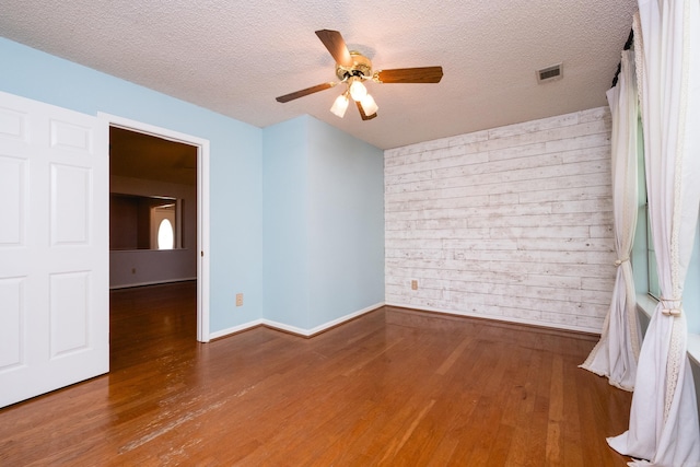 empty room with baseboards, ceiling fan, wood finished floors, and visible vents
