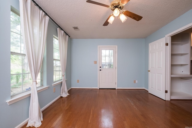 interior space with visible vents, wood finished floors, baseboards, plenty of natural light, and a textured ceiling