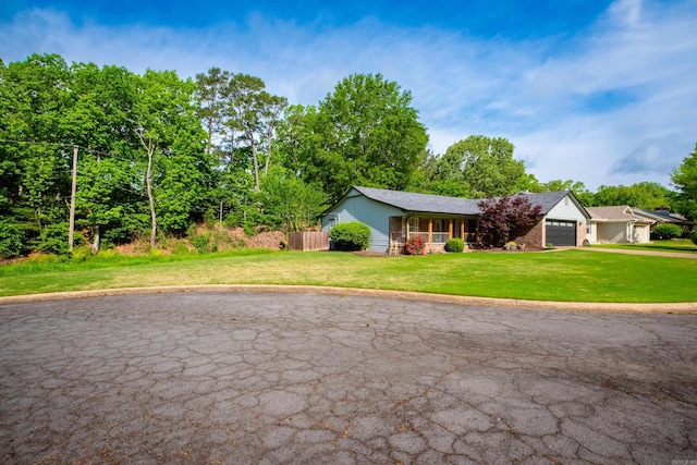 ranch-style house with a front lawn, aphalt driveway, fence, an attached garage, and a porch