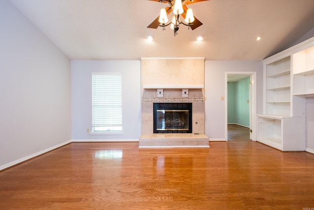 unfurnished living room featuring a ceiling fan, baseboards, wood finished floors, and a fireplace