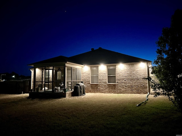 4630 Bedrock Dr, Jonesboro, AR 72404 - back of house at night featuring a sunroom, fence, and stone siding
