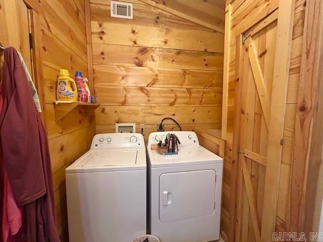 washroom with wooden walls, laundry area, independent washer and dryer, and visible vents