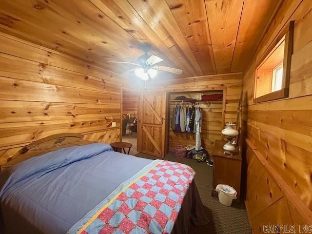 bedroom featuring a closet, wood walls, wooden ceiling, a ceiling fan, and carpet