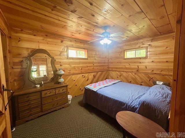 bedroom featuring wood ceiling, multiple windows, wood walls, and carpet floors