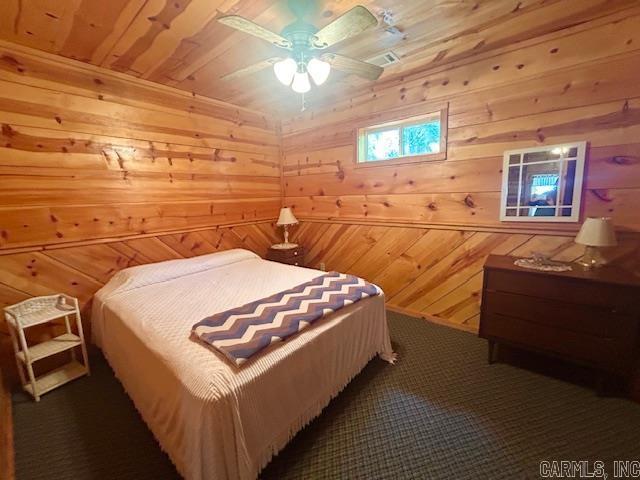 bedroom featuring wooden ceiling, carpet, a ceiling fan, and wood walls