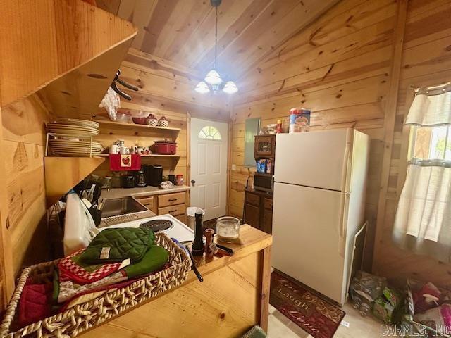 kitchen with open shelves, wood walls, wooden ceiling, freestanding refrigerator, and stainless steel microwave
