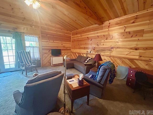 living area featuring a ceiling fan, vaulted ceiling, carpet floors, wooden ceiling, and wooden walls