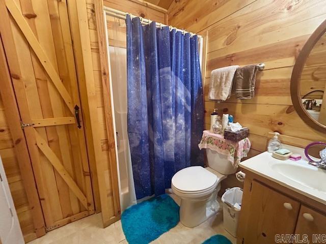 full bathroom with vanity, a shower with shower curtain, wooden walls, and toilet