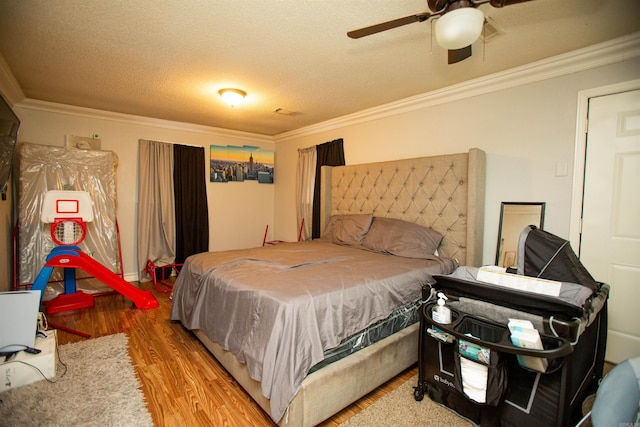 bedroom with a ceiling fan, a textured ceiling, ornamental molding, and wood finished floors