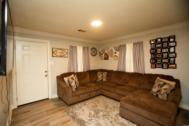 living area with visible vents, ornamental molding, baseboards, and wood finished floors