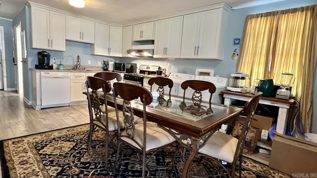 kitchen with light wood-type flooring, light countertops, white cabinetry, a sink, and appliances with stainless steel finishes