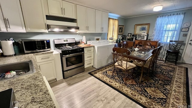 kitchen with independent washer and dryer, crown molding, light wood-style floors, stainless steel appliances, and white cabinetry